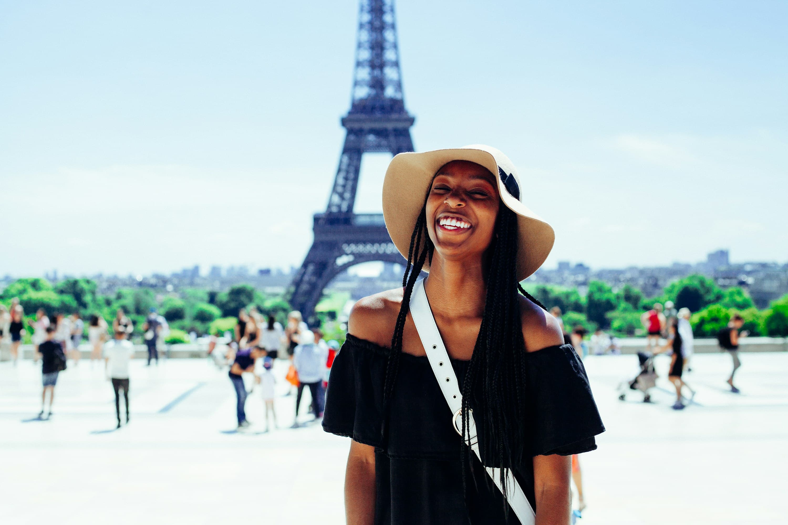 Smiling traveler in a sun hat in front of the Eiffel Tower